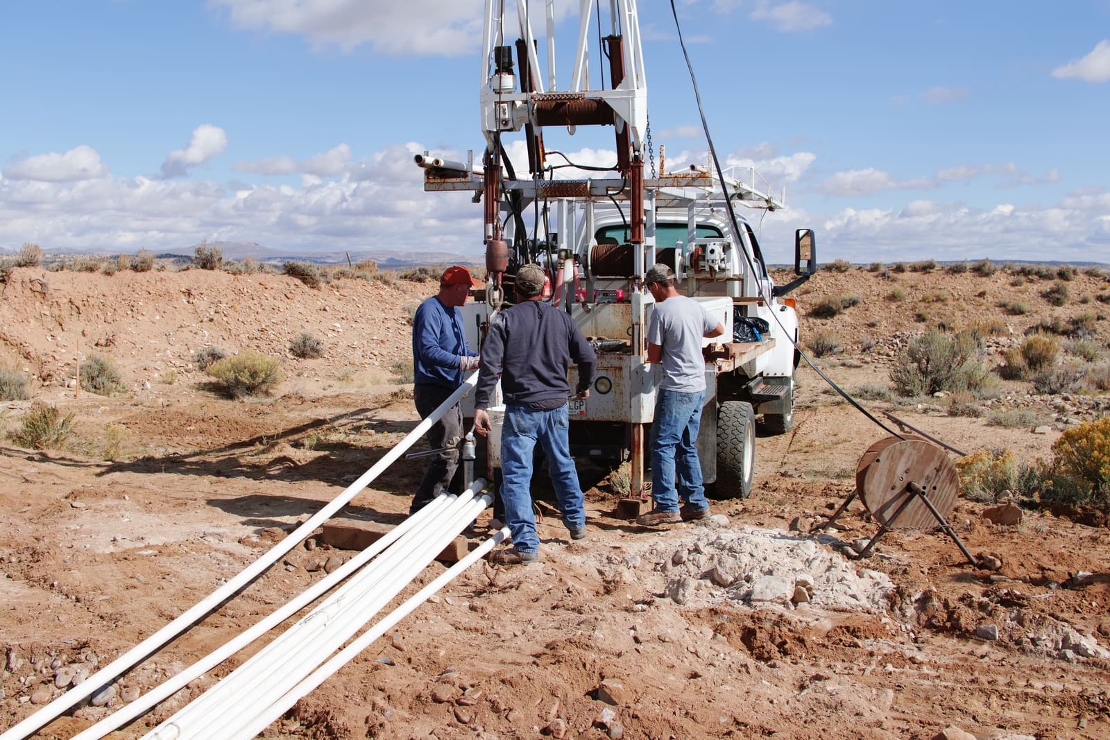 A drill crew working around a truck-mounted rig on the placer ground, with sample pipe laid out.